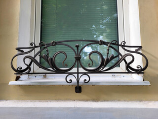 A white window with a black wrought-iron lattice for placing flower pots