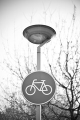 Bicycle lane sign under street lamp in monochrome