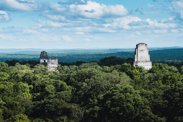 Lost city of Tikal appearing above lush jungle vegetation, showcasing the grandeur of Mayan...