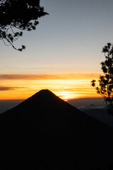 Sunrise spectacle from Acatenango with glowing clouds wrapping around Volc&aacute;n de Fuego in a dramatic mountain scene