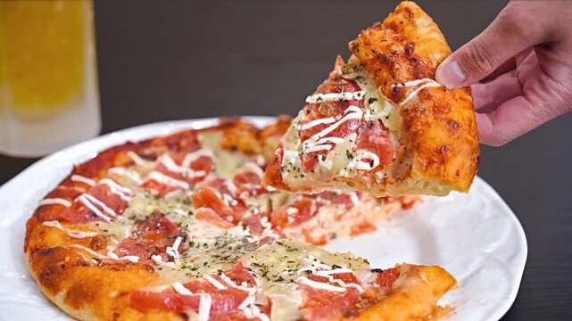 トマトいっぱいピザをもつ男性の手元と生ビール
