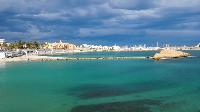 Panorama: Moody seascape at Monastir, Tunisia, Mediterranean sea reflecting dramatic storm clouds and soft light near the horizon, conveying tranquility, travel mood, and coastal atmosphere