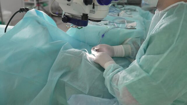 Professional ophthalmologist performing a delicate cataract operation on a patient's eye using modern surgical microscope and equipment