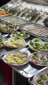 Vertical video of fresh seafood in shell at a nighttime market in Vietnam's Phu Quoc Island.