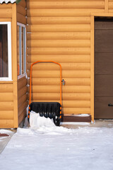 A snow scraper stands near the wall.