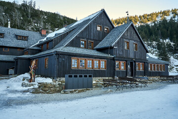 The wooden building of the Samotnia tourist shelter during winter in the Karkonosze Mountains © GKor