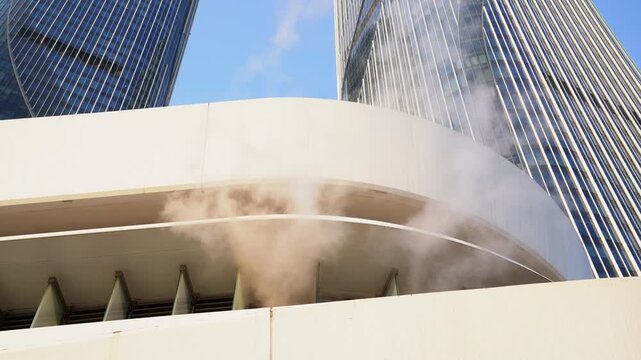 Smoke rising from ventilation outlet on modern building rooftop in urban setting