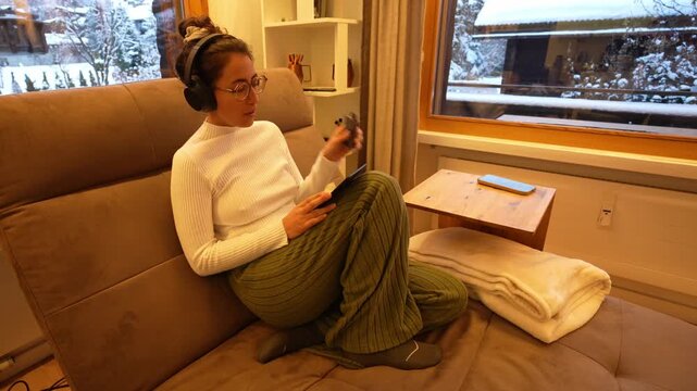 Woman relaxing on sofa using e cigarette and tablet