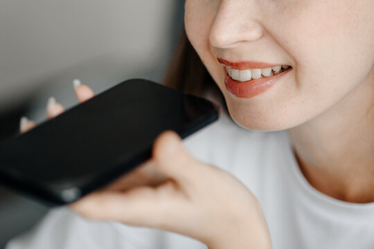 young beautiful caucasian brunette woman recording voice message, smiling widely, casual clothes, white T-shirt, talking by smartphone