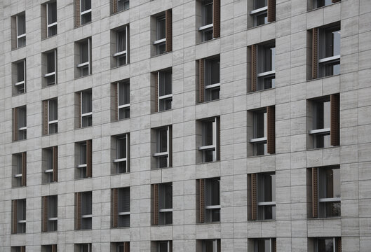 many rows of glass windows frames on large square grey concrete tiles wall of business office building. front view. gray tiled exterior. Belgrade Serbia City town centre
