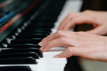 Obraz premium female pianist hands on black and white synthesizer keyboard, close-up view, young woman playing piano, professional musician