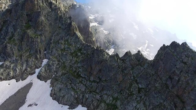Aerial timelapse of sharp rocky alpine mountain peaks in summer across high altitude USA ranges. Rugged cliffs and exposed ridgelines reveal dramatic geology under clear blue sky.