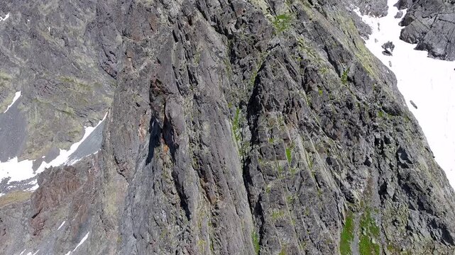 Aerial timelapse of sharp rocky alpine mountain peaks in summer across high altitude USA ranges. Rugged cliffs and exposed ridgelines reveal dramatic geology under clear blue sky.
