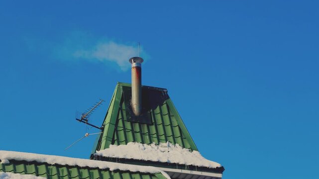 Close-up winter view of a residential house metal roof with a ventilation pipe emi