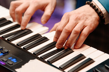 Fototapeta premium male pianist hands on black and white piano keyboard, close-up view, young man playing piano, professional musician