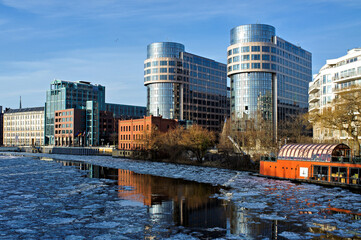 Modern glass office buildings in berlin at the riverfront with floating ice during winter