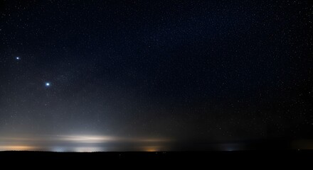 Obraz premium Distant Lights Reflect on Water Under a Starry Night Sky.