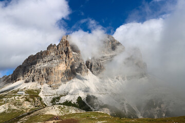 Alpine trail perspective of Tre Cime di Lavaredo beneath white clouds