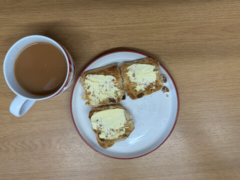 Hot Cross Buns with One Eaten and Mug of Tea