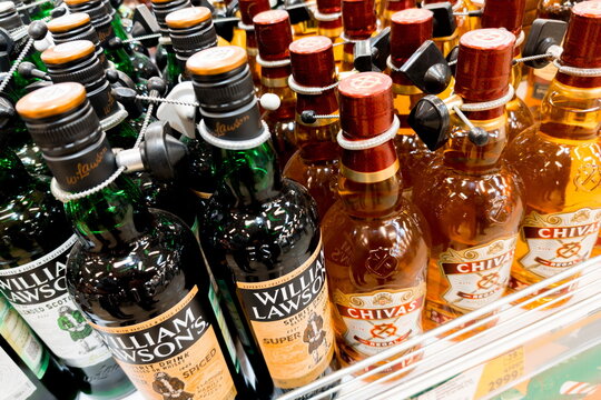 William Lawson's and Chivas Regal whiskey bottles arranged on shelves in a store during daytime shopping hours