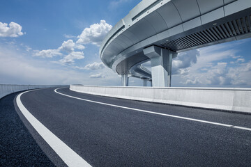 An empty asphalt road and a modern overpass under a clear blue sky on a sunny day © ABCDstock
