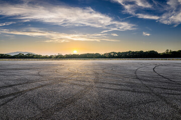 Naklejka premium An empty asphalt road and tire tracks under a beautiful sunset sky