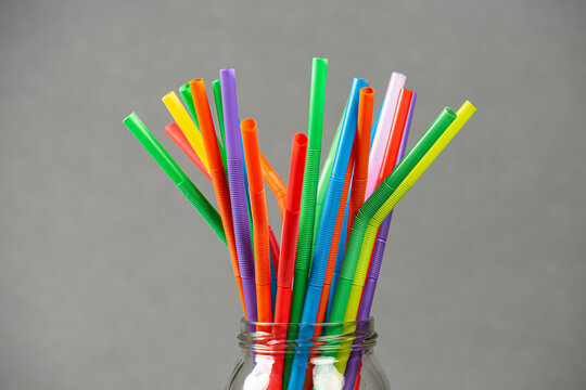 Colorful flexible plastic drinking straws arranged in glass jar.