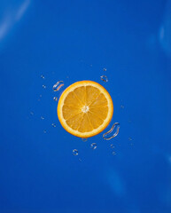 Vibrant orange slice with water droplets on blue background