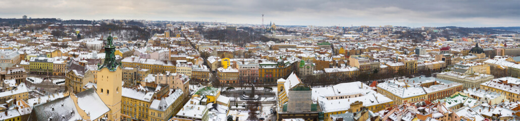 Obraz premium Lviv, Ukraine, Western Europe panoramic winter cityscape from Town Hall tower, Latin Cathedral and Opera House architecture with snowy rooftops on Svobody Avenue under gray sky, urban tourism.