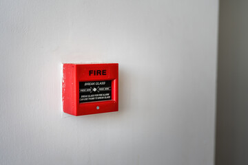 Fire alarm box on white wall, breaking glass and push the button to activate sound alarm. Safety equipment object for building place. Close-up. 