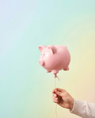 Person holding pink pig balloon symbolizing financial growth