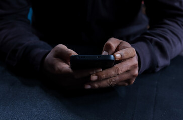 Phone scammers, unrecognizable man holding a smartphone, anonymous cyber criminal performing...