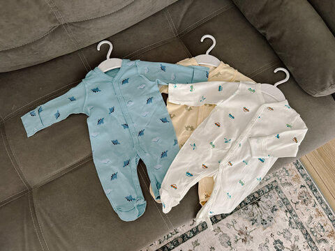 Set of sleepsuits for newborns made of cotton with buttons on gray sofa. The sewing seams are out