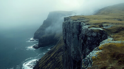 Fototapeta premium Remote island shoreline cliff fog Atlantic coast, rugged sea stack under moody sky