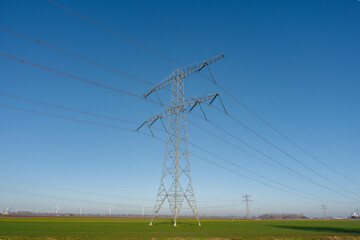 Power lines stretch across the horizon on a clear, bright day.