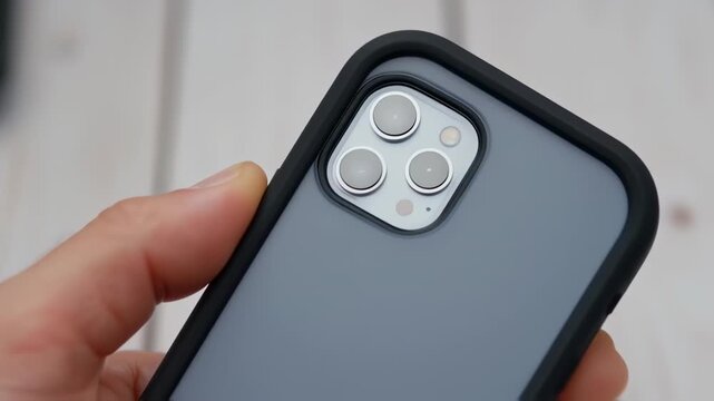 Close-up of a smartphone case with a dark gray/blue phone body and black protective case.  Four camera lenses are visible