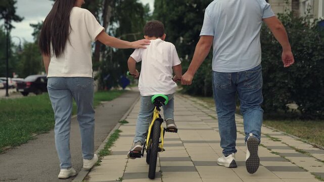 boy laughs smiling sitting bike outdoors, child boy toothless smile, father teaches child kid boy son ride bike outdoors, child kid boy son learns ride bike, child dream of traveling, happy family