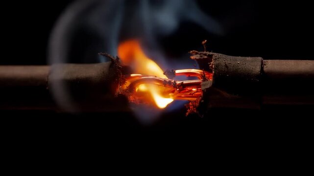 Closeup of a burning electrical wire with flames and smoke