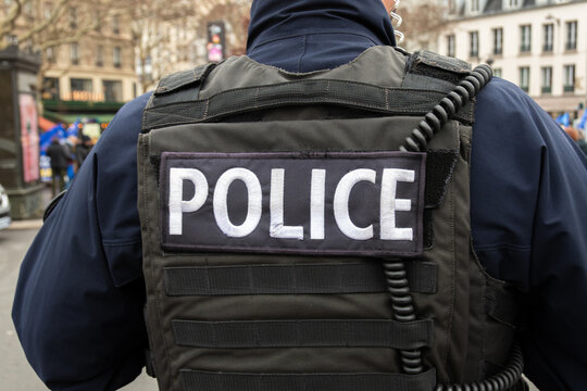 Gros plan du marquage "POLICE" &eacute;crit &agrave; l'arri&egrave;re du gilet tactique d'un officier de police fran&ccedil;ais dans une rue de Paris. Concepts de forces de l'ordre, de crime et d'investigations en France