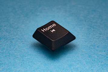 Single black computer keyboard home key isolated on blue textured background. Symbolizing navigation, return, user interface, technology concepts and minimal digital workspace design.