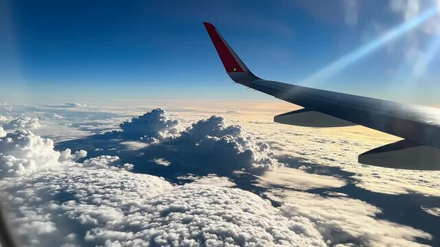 Airplane wing flying over clouds at sunset, aerial view, travel concept