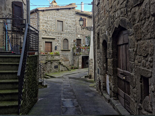 Fototapeta premium A narrow alleyway in the ancient town of Vitorchiano, Italy, defined by unique external stone staircases and grey volcanic rock buildings