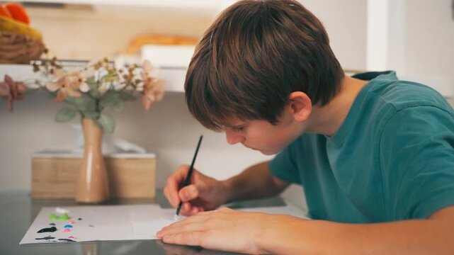 Teenager developing creativity and motor skills through painting. Artistic development, learning and imagination at home.