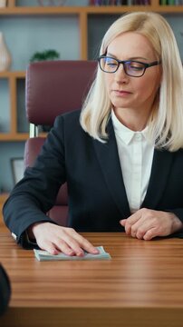 Attractive righteous strict business lady refuses a bribe in the form of dollar bills offered to her by unrecognizable bearded unscrupulous entrepreneur in office