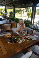 Elegant Indulgence: A woman is enjoying a delightful brunch, surrounded by a table laden with fresh, appetizing dishes and refreshing beverages.
