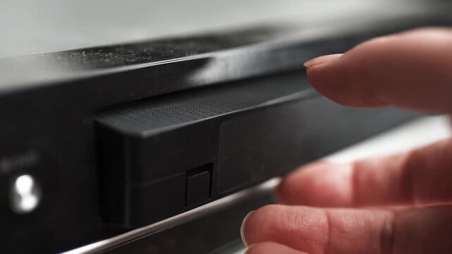 Close up of a hand holding a videotape. Retro vhs cassete in a player.	
