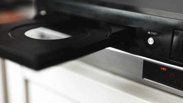 Woman puts a dvd disc into media player.	
