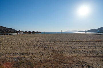 View of a wooden pathway stretching across soft sand towards the open beach of Mylopotas in Ios Greece