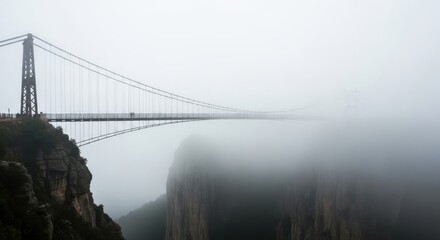Misty suspension bridge stretches through dense fog.