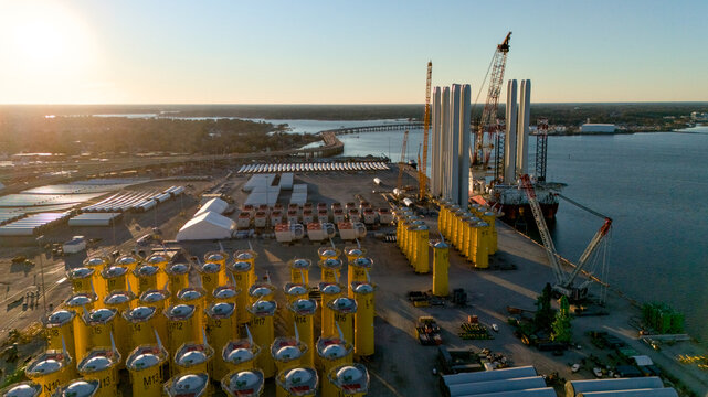 Drone photo of port logistics hub with wind turbine tower sections and infrastructure